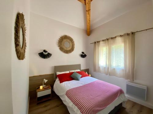 une chambre avec un lit avec des oreillers rouges et une fenêtre dans l'établissement Appart Cala Rossa - Porto-Vecchio - Mer à pied, à Lecci