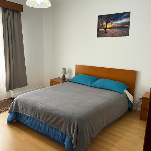 a bedroom with a large bed with blue pillows at Espaço perto aeroporto in Ponta Delgada