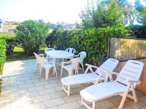 d'une terrasse avec des chaises blanches, une table et des chaises. dans l'établissement Apartment Coudalère-Guadeloupe-10 by Interhome, au Barcarès