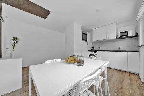a white kitchen with a white table and chairs at PEARL06 Appartement cosy près de Bienne 1D in Pieterlen