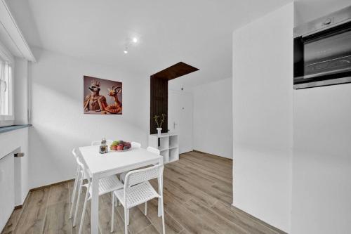 a white dining room with a white table and chairs at PEARL06 Appartement cosy près de Bienne 1D in Pieterlen
