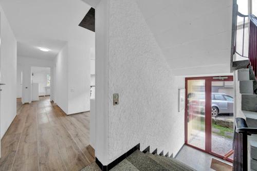 a hallway with white walls and wooden floors and a door at PEARL06 Appartement cosy près de Bienne 1D in Pieterlen