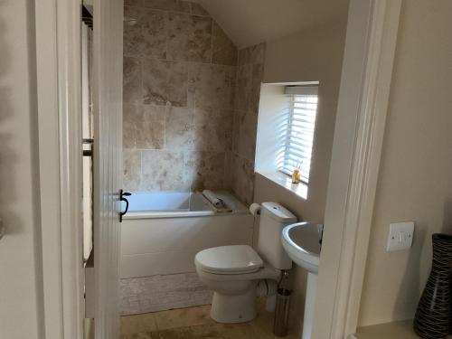a bathroom with a toilet and a tub and a sink at Beckside in Lastingham