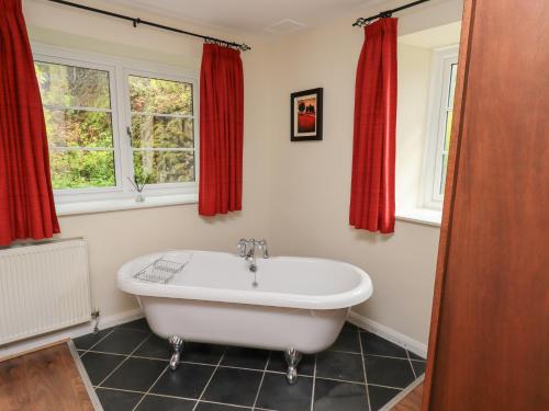 a white bath tub in a bathroom with red curtains at The Old Chapel in Windermere