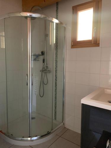 une douche en verre dans une salle de bain avec un lavabo dans l'établissement Villa proche du plan d'eau, à Embrun