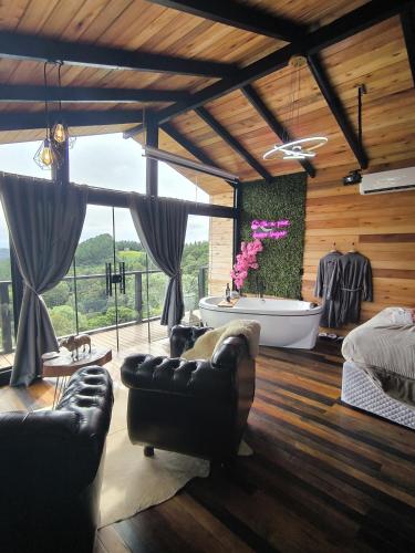 a living room with a tub and a couch at Chalé Recanto da Coruja 2 in Barracão