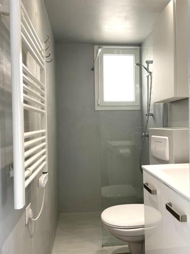 a white bathroom with a toilet and a window at TUSQUETS - Apartamento con vistas al mar in Cadaqués