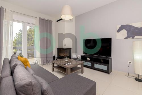 a living room with a gray couch and a tv at Luxurious Tsimiski 3BDR 3rd Floor in Alexandroupoli