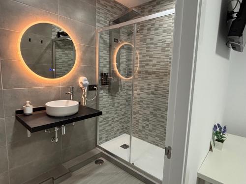 a bathroom with a sink and a glass shower at Hostal Los Mellizos in Conil de la Frontera