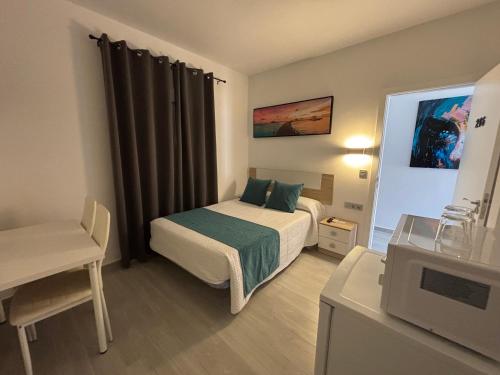 a small bedroom with a bed and a television at Hostal Los Mellizos in Conil de la Frontera