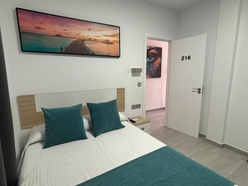 a bedroom with a bed with blue pillows at Hostal Los Mellizos in Conil de la Frontera