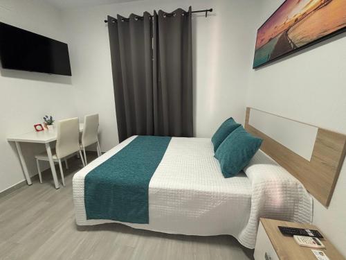 a bedroom with a bed and a table and a desk at Hostal Los Mellizos in Conil de la Frontera