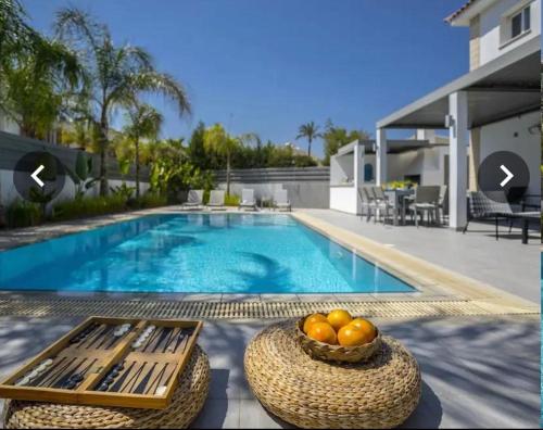 a swimming pool with a bowl of fruit next to a house at Sandy Feet Beach House in Paralimni