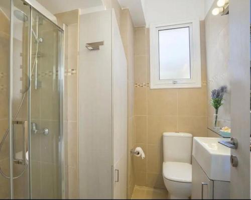 a bathroom with a shower and a toilet and a sink at Sandy Feet Beach House in Paralimni