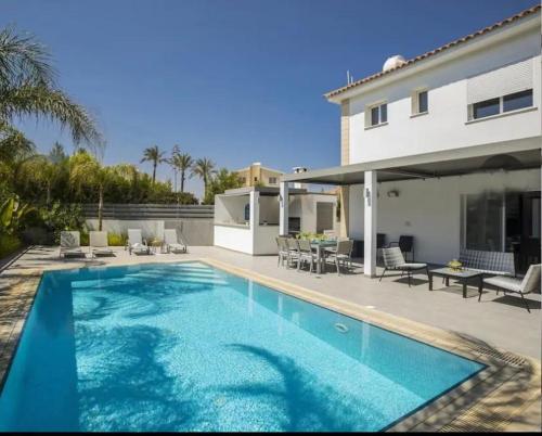 a swimming pool in front of a house at Sandy Feet Beach House in Paralimni