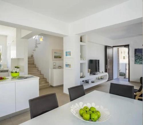 a kitchen and dining room with a table with a bowl of fruit at Sandy Feet Beach House in Paralimni
