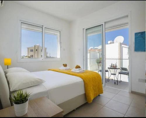 a white bedroom with a large bed and a balcony at Sandy Feet Beach House in Paralimni