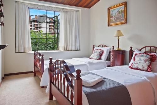 une chambre avec deux lits jumeaux et une fenêtre dans l'établissement Capivari - Lareira - Estilo Clássico de Casa de Campo, à Campos do Jordão