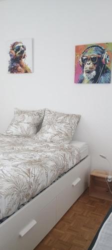 a bedroom with a bed with two paintings on the wall at Comfortable 1 bd apt in Peseux