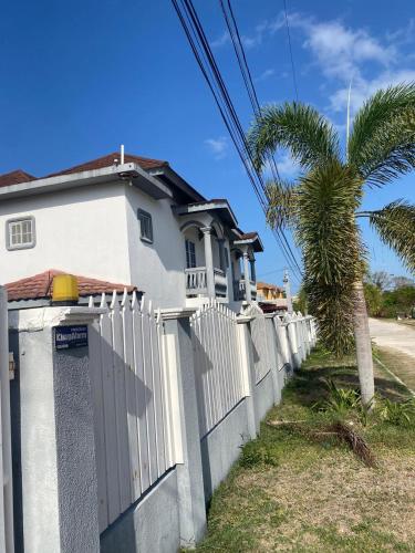 a white house with a fence and a palm tree at Sukasa Ville in Montego Bay