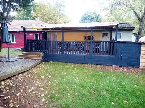 a house with a porch with a blue fence at camping la lande in Mimizan