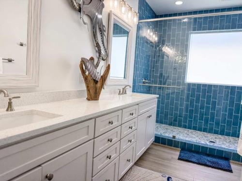 a bathroom with a sink and blue tiles at Serenity by the Sea St George Island Pool Home in Eastpoint
