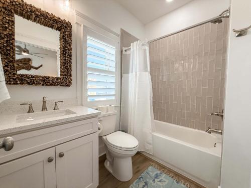 a white bathroom with a toilet and a tub and a sink at Serenity by the Sea St George Island Pool Home in Eastpoint