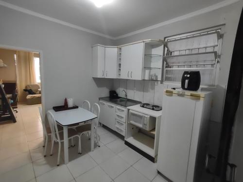 フロリアノポリスにあるApto studio no Centro de Floripa 201の白いキャビネットとテーブル、そして小さなテーブルと椅子のあるキッチン