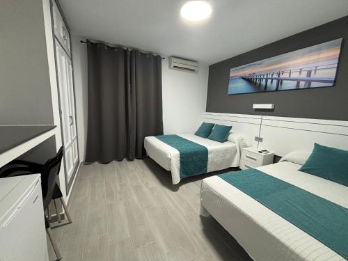 a hotel room with two beds and a tv at Hostal Los Mellizos in Conil de la Frontera