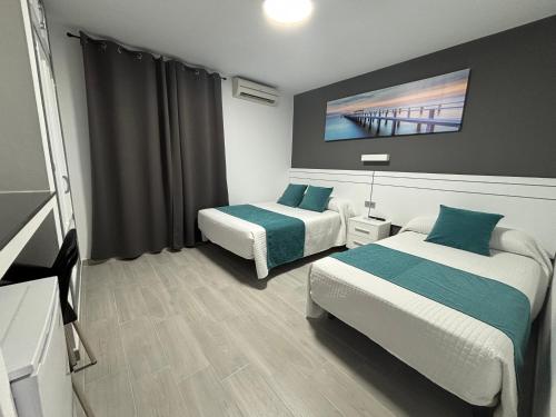 a hotel room with two beds and a tv at Hostal Los Mellizos in Conil de la Frontera