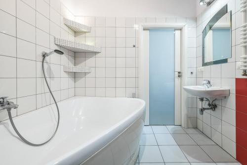 a white bathroom with a tub and a sink at Neptun Park by NorthSide Apartments in Gdańsk