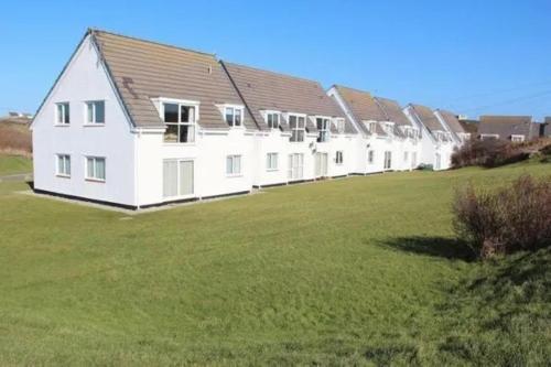 a large white house in a field of grass at 7 Isallt Lodges-3 bed-Ground Floor-Outside seating in Trearddur