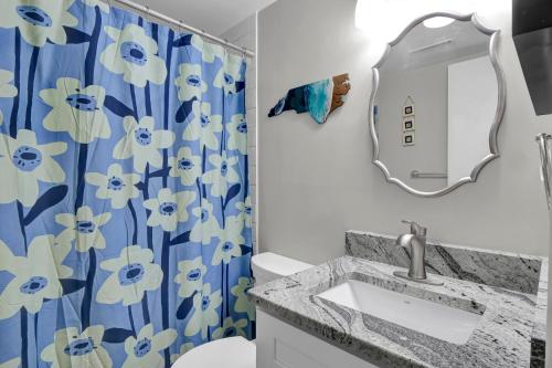 a bathroom with a sink and a blue and white shower curtain at Alternate Destination in North Topsail Beach