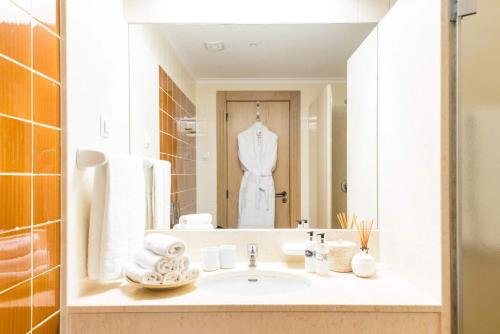 a bathroom with a sink with a white suit in the mirror at Birdsong Vila Sol Village by Experience MamiMi in Vilamoura