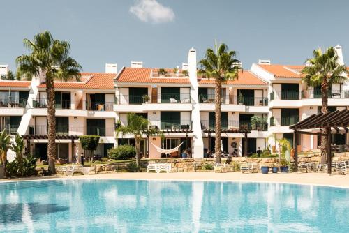 a swimming pool in front of a hotel at Birdsong Vila Sol Village in Vilamoura