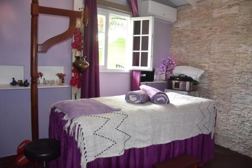 a bedroom with a bed with purple sheets and a window at Gites d'Arles Bungalow T1 BIS in Le Moule