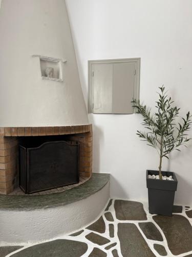 a living room with a fireplace and a potted plant at Lithari Traditional Apartment in Agios Sostis