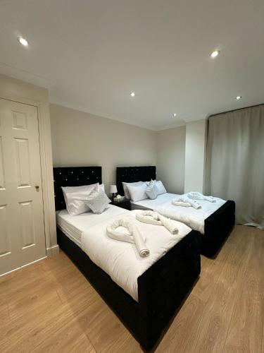 two beds in a hotel room with phones on them at 2 Bedroom Flat with 24 7 security and concierge in London