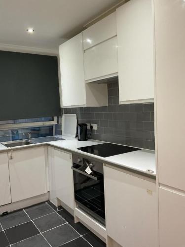 a kitchen with white cabinets and a black sink at 2 Bedroom Flat with 24 7 security and concierge in London