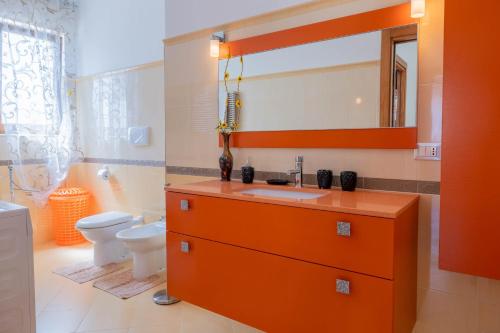 ein orangefarbenes Badezimmer mit einem Waschbecken und einem WC in der Unterkunft VILLA LAURA in Carovigno