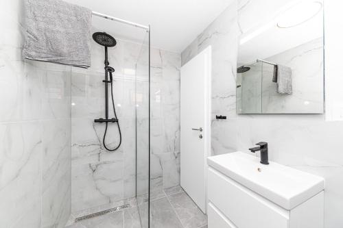 a white bathroom with a shower and a sink at Apartman Simic in Trogir
