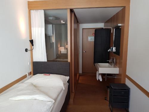 um pequeno quarto com uma cama e um lavatório em East West Hotel Basel em Basileia