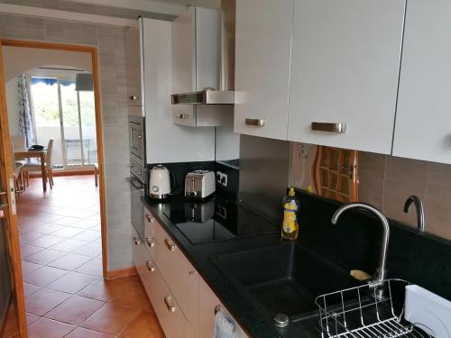 une cuisine avec un évier et un plan de travail noir dans l'établissement L'idéal entre centre ville, mer et colline, à Toulon