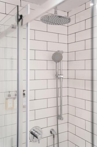 a shower in a bathroom with white tiles at Maison Saint-Vincent By Maisons & co in Montréal