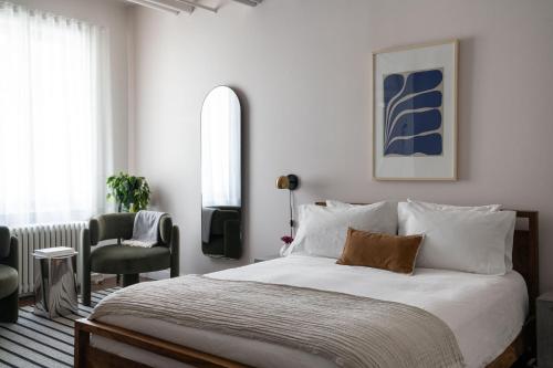 a bedroom with a large bed and a chair at Maison Saint-Vincent By Maisons & co in Montréal