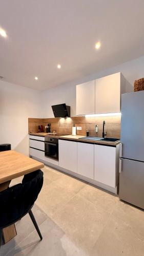 - une cuisine avec des placards blancs, une table et un réfrigérateur dans l'établissement Résidence Collioure le Haut, à Collioure