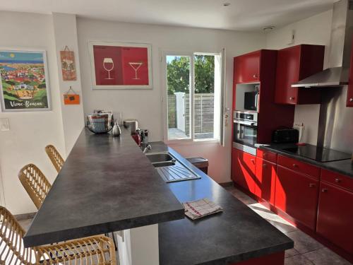 une cuisine avec des armoires rouges et un comptoir noir dans l'établissement Villa Pignon, à Vieux-Boucau-les-Bains