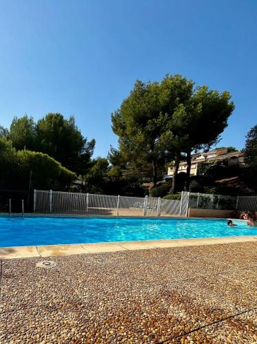 une piscine avec de l'eau bleue et des arbres en arrière-plan dans l'établissement Quiet apartment and sea view, à Bandol