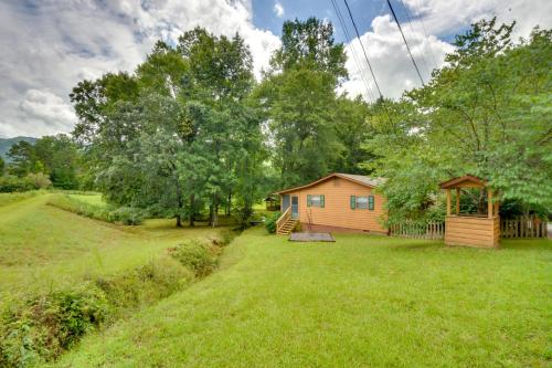 a small house in a field with a yard at Grand Murphy Cabin with Fire Pit and Game Room! in Murphy