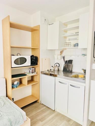 une petite cuisine avec des armoires blanches et un micro-ondes dans l'établissement Studio Île de Nantes, à Nantes